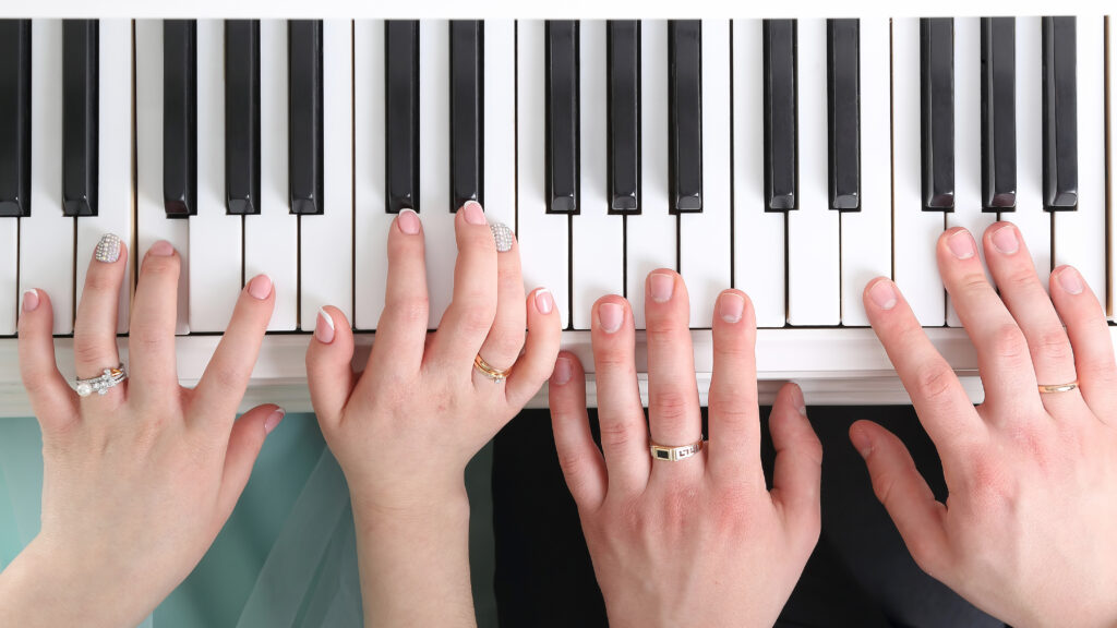 Foto de dos personas tocando el piano a cuatro manos