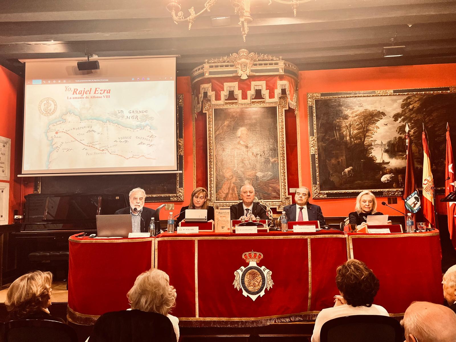 Fotografía horizontal de ponentes en una mesa principal durante una presentación de libro con público en primer plano.
