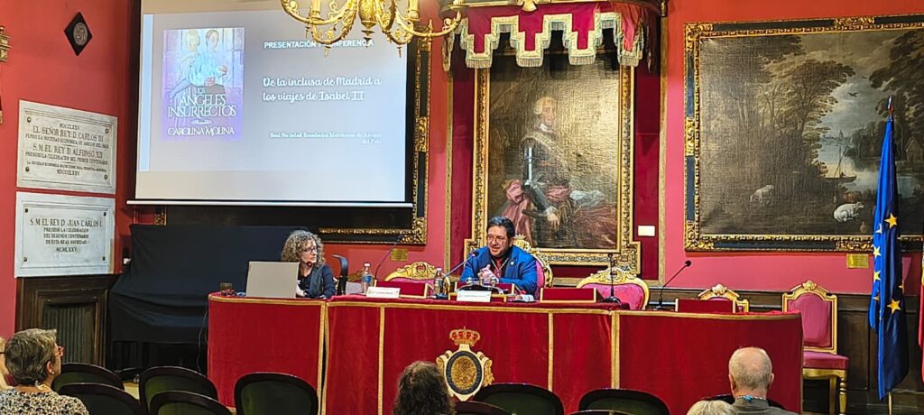 Dos participantes intervienen ante los micrófonos, con una presentación sobre el arte mudéjar madrileño proyectada en pantalla.