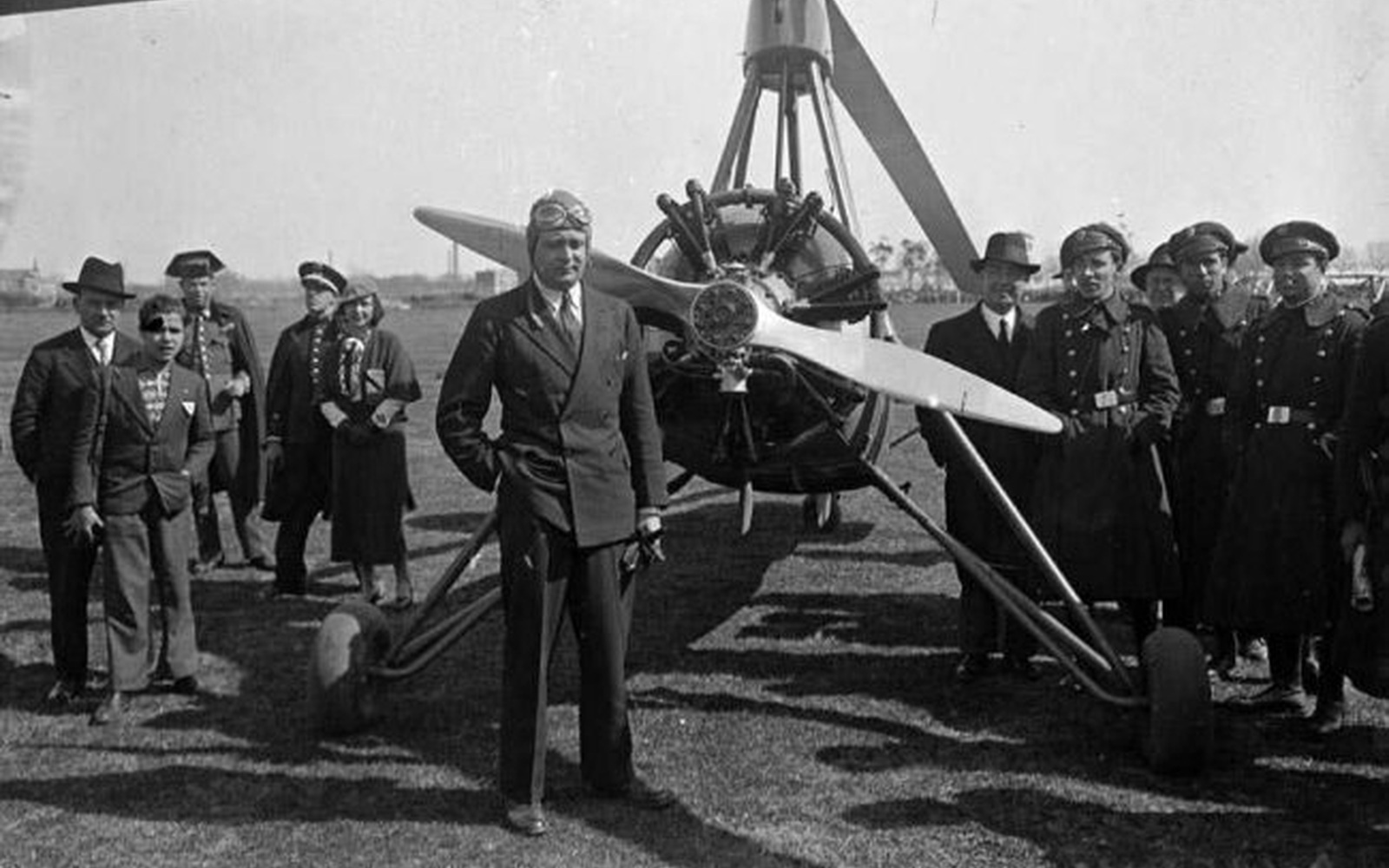 Grupo de personas posa junto a un autogiro en un aeródromo.