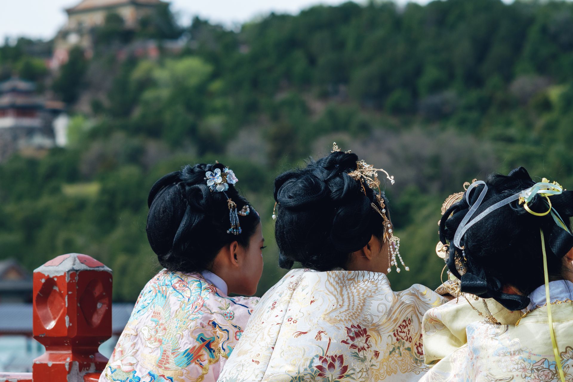 Tres mujeres vistas de espaldas con vestimenta tradicional china y elaborados adornos en el cabello.