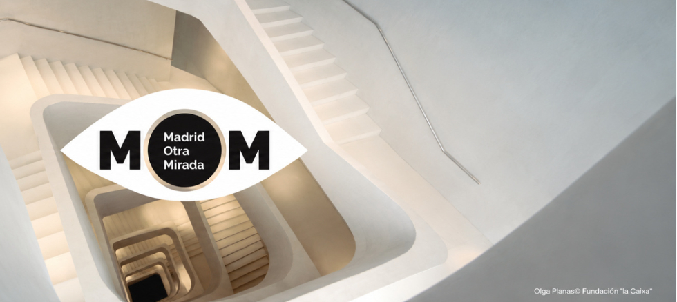 Logotipo de Madrid Otra Mirada (MOM) sobre una vista cenital de una escalera interior blanca de formas geométricas; en la esquina inferior derecha figura el crédito «Olga Planas © Fundación “la Caixa”».