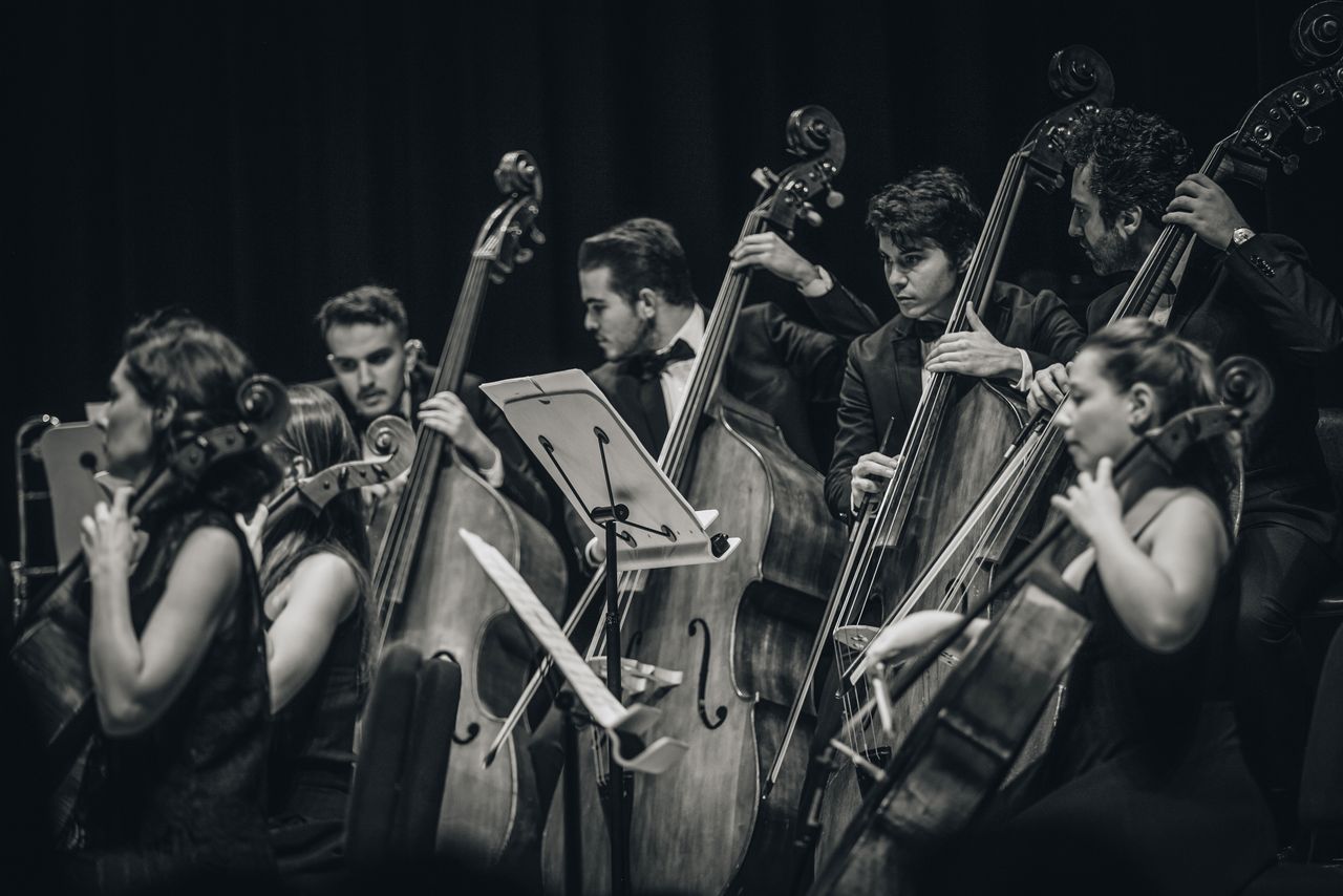 Fotografía en blanco y negro de músicos interpretando instrumentos de cuerda en un concierto.